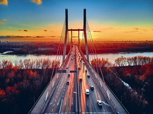 Vacker panorama antenn drönare utsikt över kabel-stannade Siekierkowski Bridge över floden Vistula och Warszawa City skyskrapor, Polen i guld röda höstfärger i november kväll vid solnedgången — Stockfoto