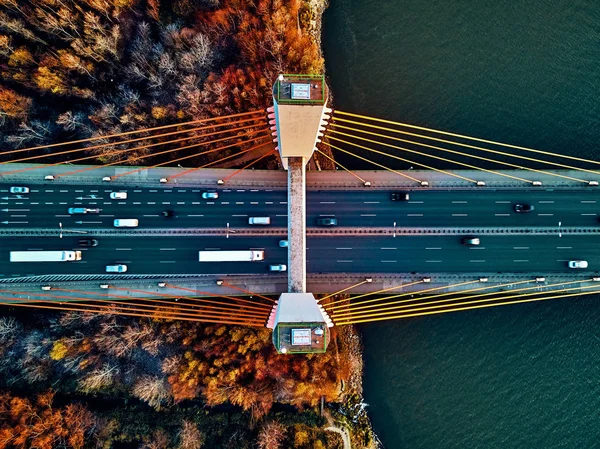 Beautiful panoramic aerial drone view to cable-stayed Siekierkowski Bridge over the Vistula river and Warsaw City skyscrapers, Poland in gold red autumn colors in November evening at sunset - top down — Stock Photo, Image