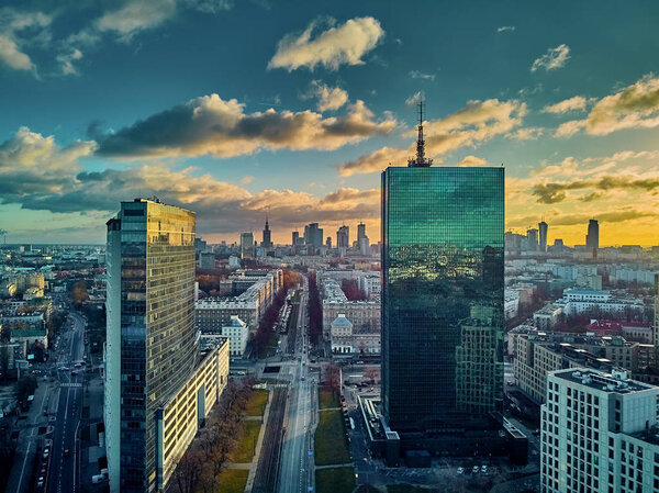 Beautiful panoramic aerial drone view to the ?enter of modern Warsaw city with silhouettes of skyscrapers in in the rays of the setting winter January sun - amazing sunset, Poland