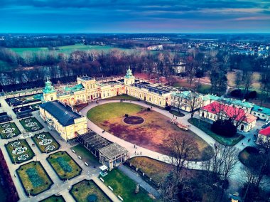 Beautiful panoramic aerial drone view to Wilanow Palace or Wilanowski Palace - is a royal palace located in the Wilanow district, Warsaw, Poland in gold red colors at warm January sunset clipart