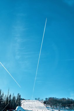 Konsantrasyonun kış kayak yamacının üzerinde gökyüzünde bulunan bir uçağın yoğunlaşma izi (ters dönüş izi, jet izi) - Polonya 'nın güneyindeki güzel kış dağ manzarası