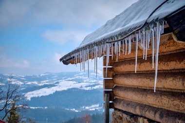 Polonya 'nın güneyinde güçlü gerçek kış - çatıdan sarkan büyük buzullar mavi güneşli gökyüzüne karşı