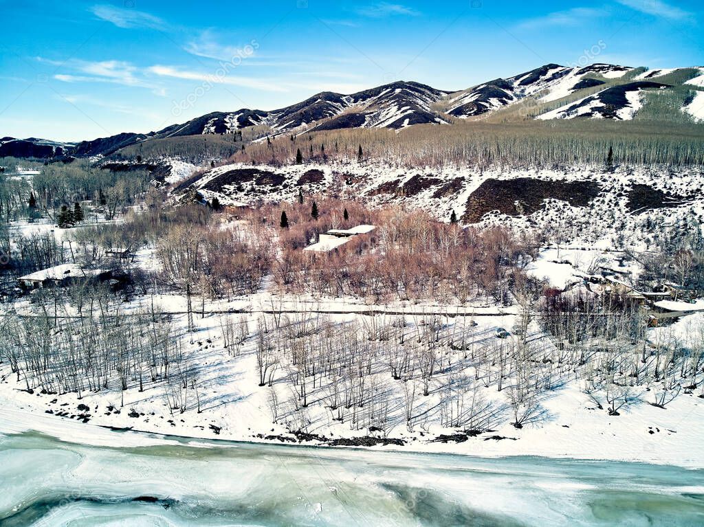 Panoramic aerial view: beautiful spring landscape: the Ulba river in Kazakhstan wakes up from winter sleep - ice drift - snow and ice are melting in the mountains, the bright sun is shining, Qazaqstan