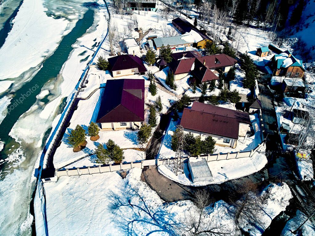 Panoramic aerial view: beautiful spring landscape: the Ulba river in Kazakhstan wakes up from winter sleep - ice drift - snow and ice are melting in the mountains, the bright sun is shining, Qazaqstan