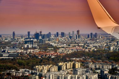 Güzel panoramik şehir manzarası - Varşova 'nın merkezine inen uçağın penceresinden manzara (Polonya) gökdelenlerle, parklarla ve yerleşim alanlarıyla, bahar başında gün batımında
