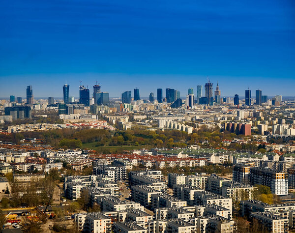 Beautiful panoramic aerial cityscape - view from the window of the plane landing at the center of Warsaw (Poland) with skyscrapers, with parks and residential areas, early spring at sunset