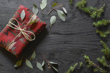 Kırmızı kumaş okaliptüs ile siyah ahşap bir masa üzerinde present.