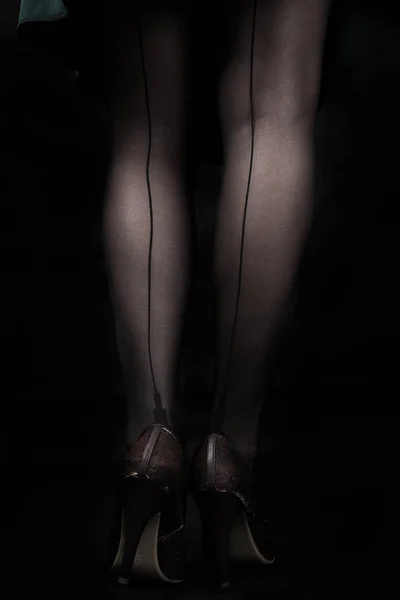 Sierlijke vrouwelijke benen in zwarte kousen met pijlen Stockfoto