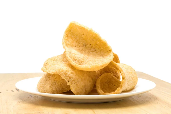 Pile of crunchy prawn cracker in a white plate on a wooden board — Stock Photo, Image