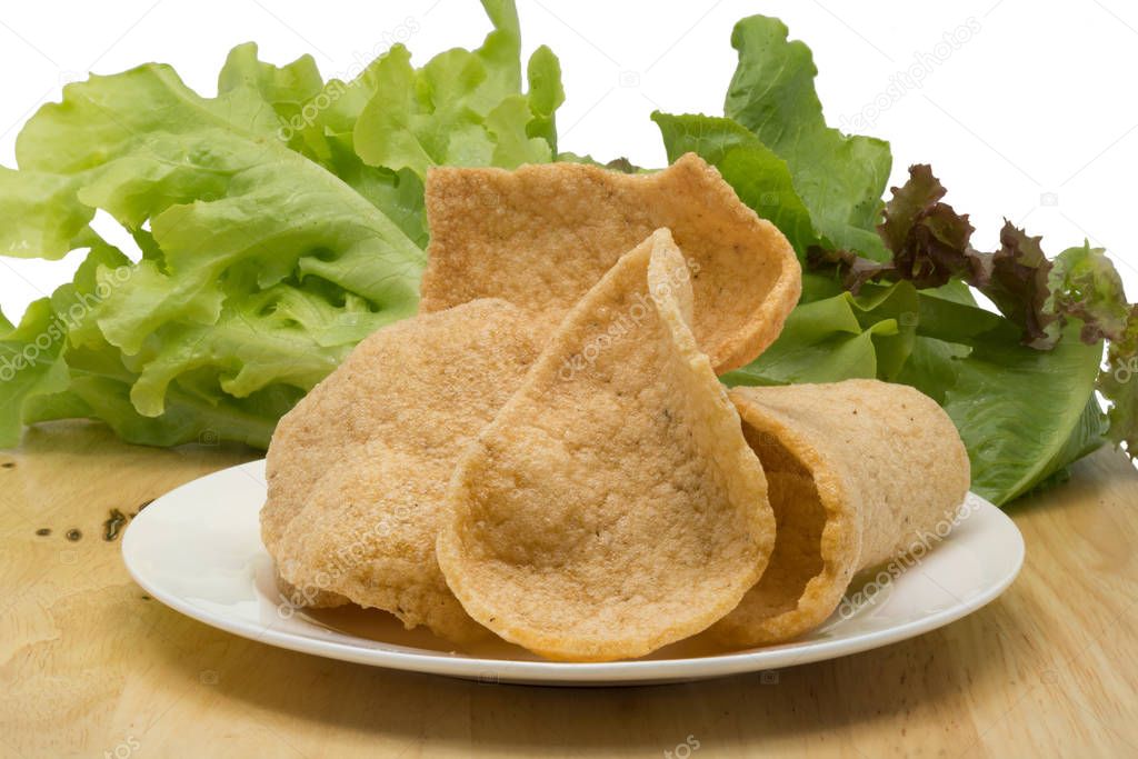 Prawn cracker and vegetables in a white plate on a wooden board