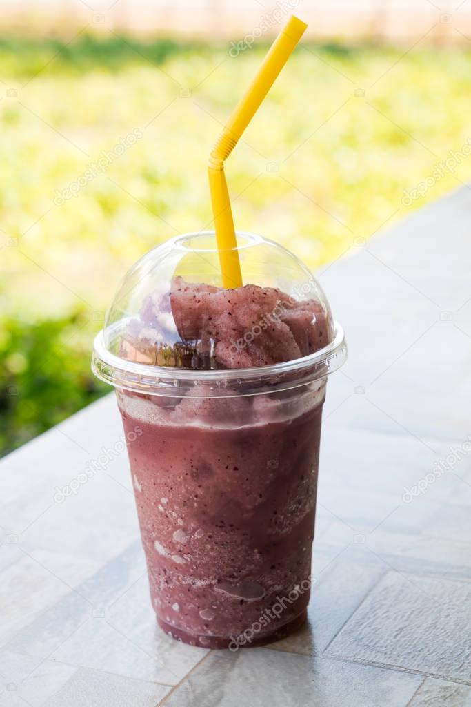 Natural grape smoothie and straw in plastic cup