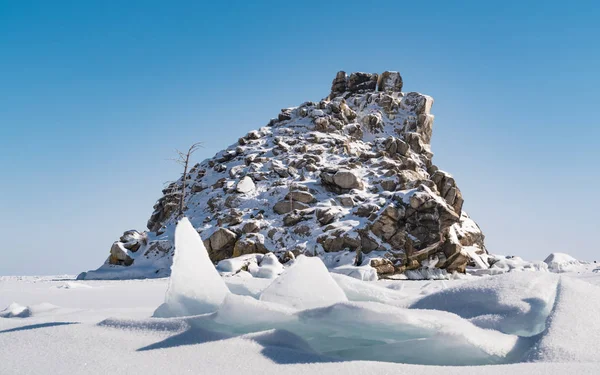 Kleine rotsachtige eiland cover met sneeuw in bevroren Baikalmeer — Stockfoto