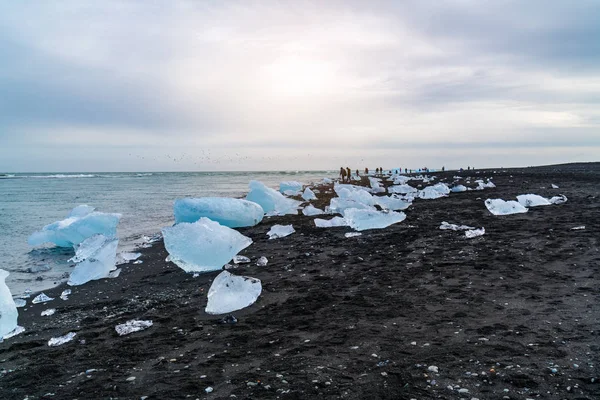 View of ice blocks and tourists on the Black Beach