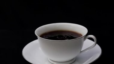 Ağır çekimde bir fincan kahvenin içine koyu kahve damlası.