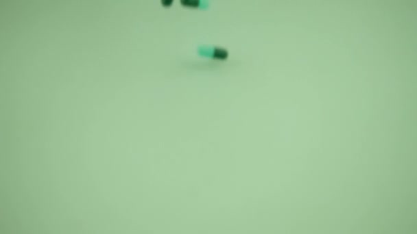 スローモーションで緑の背景に落ちる薬のカプセル — ストック動画