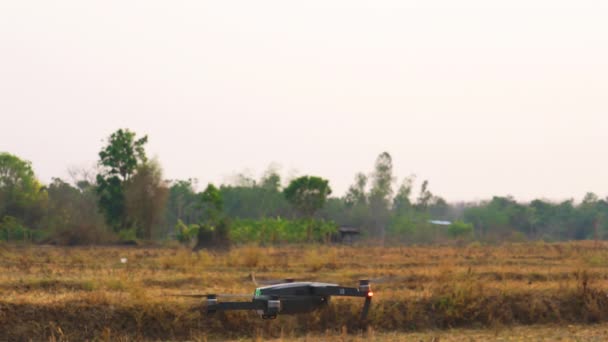 小さな無人航空機は 乾燥した収穫された水田からしばらくの間停止し 飛んで離陸する — ストック動画