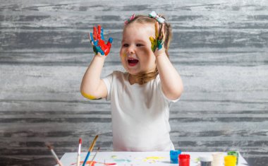 Küçük kız renkleri çiziyor. Ellerini kızın renkleri dekore edilmiştir.