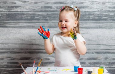 Küçük kız renkleri çiziyor. Ellerini kızın renkleri dekore edilmiştir.