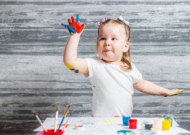 Küçük kız renkleri çiziyor. Ellerini kızın renkleri dekore edilmiştir.