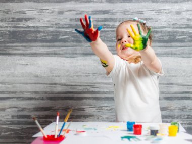 Küçük kız renkleri çiziyor. Ellerini kızın renkleri dekore edilmiştir.