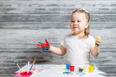 Küçük kız renkleri çiziyor. Ellerini kızın renkleri dekore edilmiştir.