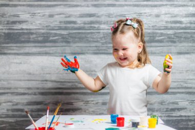 Küçük kız renkleri çiziyor. Ellerini kızın renkleri dekore edilmiştir.