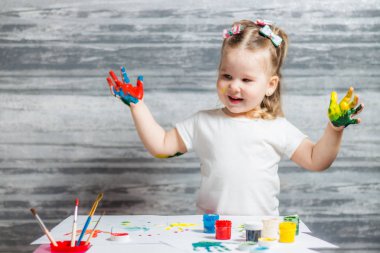 Küçük kız renkleri çiziyor. Ellerini kızın renkleri dekore edilmiştir.