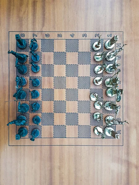 Een houten schaakbord met metalen beeldjes top uitzicht — Stockfoto