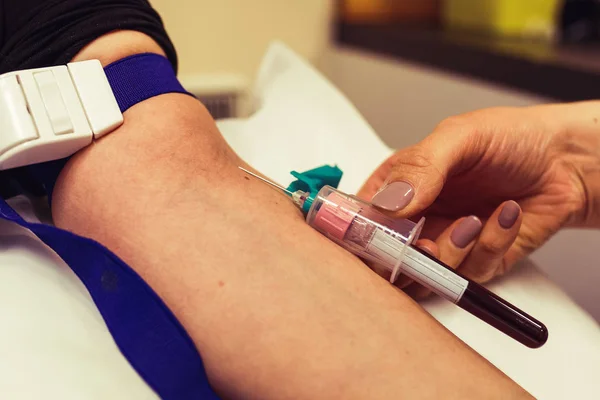 Hemşire bir hastadan kan alıyor. Coronavirus covid-19 kan enfeksiyonu. Damardan kan testi. Doppler ve kan testi hastanede. Doktor iğneyi doldururken tutuyor. Hemşire örnek alıyor..