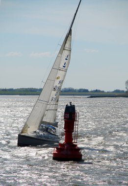 Kırmızı seyir şamandıra, beyaz yelkenli tekne yüzen