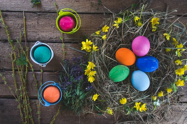 Multi-colored Easter eggs on a wooden background in the nest. — Stock Photo, Image