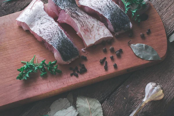 Skivad färsk fisk med kryddor och persilja på en träskiva. — Stockfoto