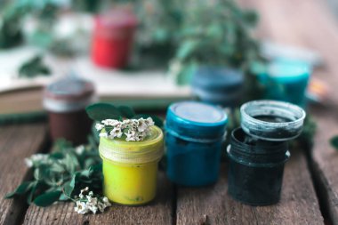 Bitkilerin yaprakları ile ahşap bir arka plan üzerinde boya kavanoz.