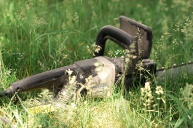 Elektrikli testere ile arka plan bulanık çimenlerin üzerinde.