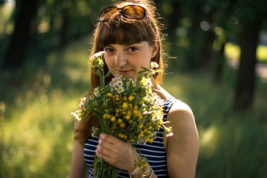 Doğada yabani çiçek bir buket ile kız.