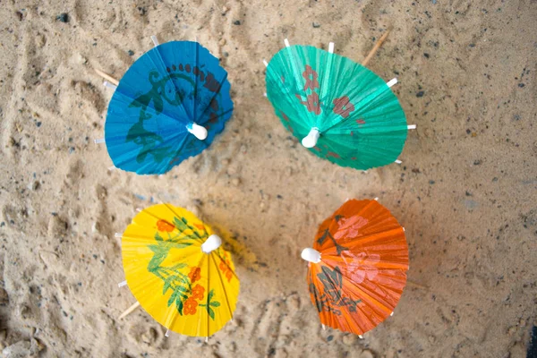 Umbrella for cocktails on a sandy summer background. — Stock Photo, Image