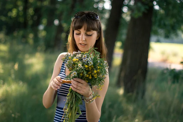 Belle fille avec un bouquet de fleurs sauvages dans la nature . — Photo