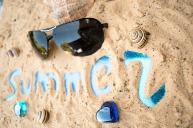 Güneşli kumlu bir plaj üzerinde siyah güneş gözlüğü.