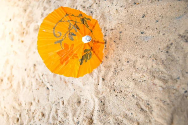 Umbrella for cocktails on a sandy summer background. — Stock Photo, Image