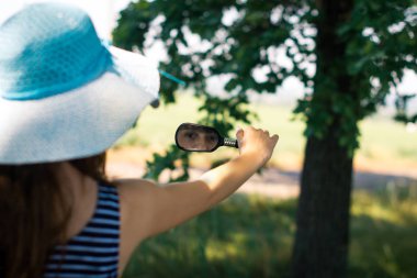 Güzel genç kız parkta aynaya bakıyor.