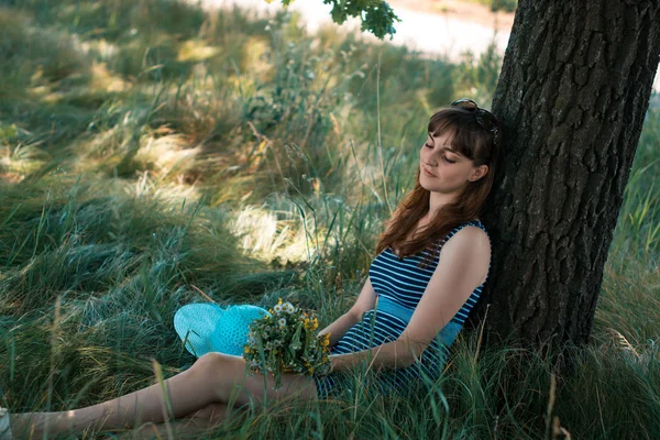 Jeune fille heureuse assise sous un arbre sur un été . — Photo
