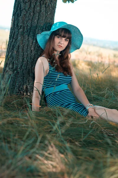 Молодая счастливая девушка, сидящая под деревом летом . — стоковое фото