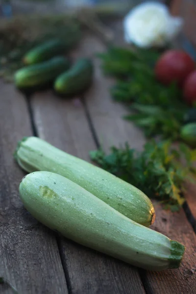 Fresh zucchini on a wooden old background with vegetables. — Stock Photo, Image