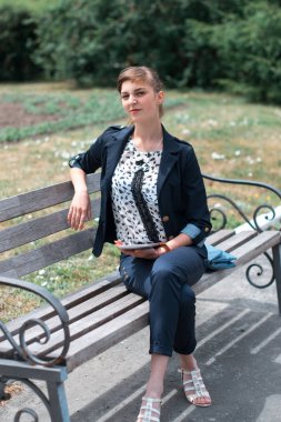 Bir tablet ile bir bankta oturan iş kadını.