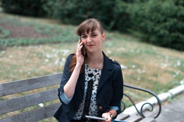 Bir tablet ile bir bankta oturan iş kadını.