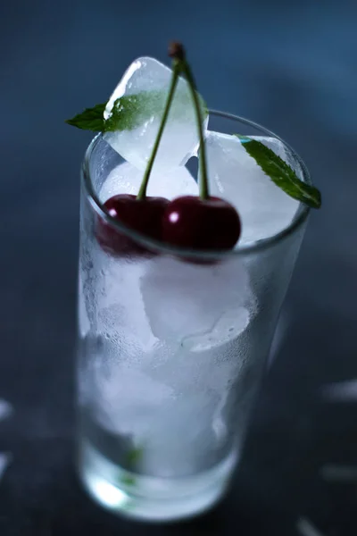 Natural ice in a glass with cherries on a black background. — Stock Photo, Image