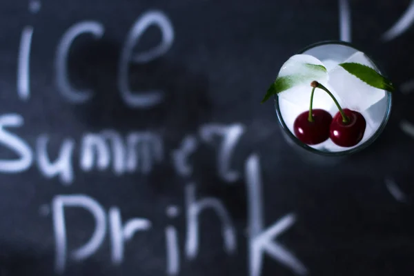 Natural ice in a glass with cherries on a black background. — Stock Photo, Image