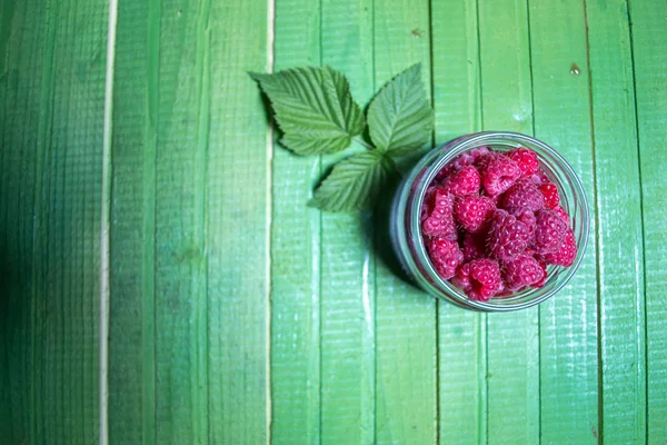 Verse rijpe frambozen op groene houten planken. — Stockfoto