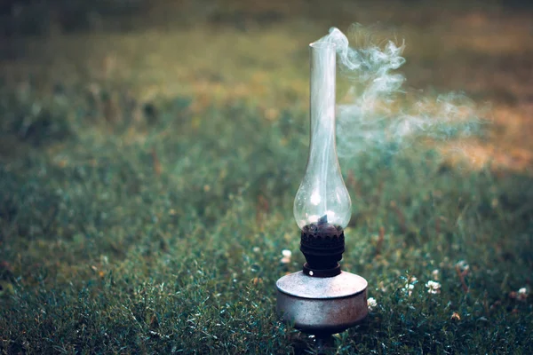 Una vieja lámpara de queroseno humeante sobre una hierba verde . — Foto de Stock