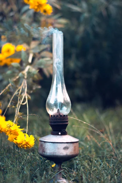 Una vieja lámpara de queroseno humeante sobre una hierba verde . — Foto de Stock